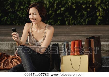 A woman with lots of shopping bags uses her cellphone View Large Photo Image Stock Image - A woman with lots of shopping bags uses her cellphone. Fotosearch