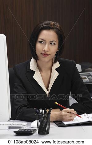 A woman working at her desk View Large Photo Image Picture - A woman working at her desk. Fotosearch