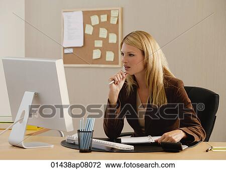 A woman works at her desk View Large Photo Image Stock Image - A woman works at her desk. Fotosearch