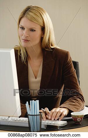 A woman works at her desk View Large Photo Image Stock Photography - A woman works at her desk. Fotosearch