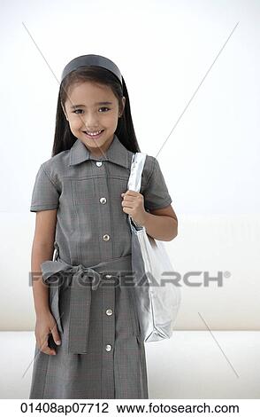 Stock Image - A young girl dressed in school uniform with a bag. Fotosearch