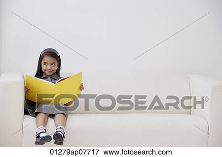 A young girl dressed in school uniform sitting down with a book View Large Photo Image Stock Photo - A young girl dressed in school uniform sitting down with a book. Fotosearch