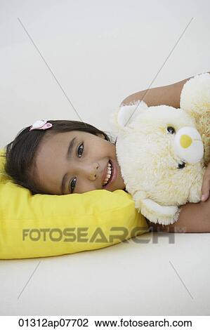 A young girl lying down with her teddy bear View Large Photo Image Stock Image - A young girl lying down with her teddy bear. Fotosearch