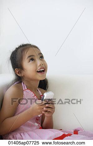A young girl plays with a cellphone View Large Photo Image Stock Photography - A young girl plays with a cellphone. Fotosearch