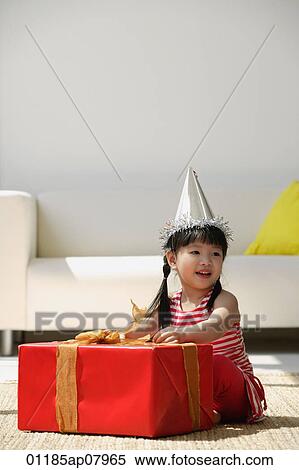 Stock Photography - A young girl unwraps a birthday present. Fotosearch