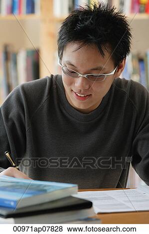 A young man studies in the library View Large Photo Image Stock Photo - A young man studies in the library. Fotosearch