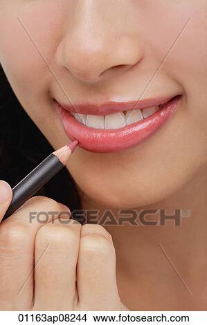 A young woman applies lip pencil View Large Photo Image Picture - A young woman applies lip pencil. Fotosearch
