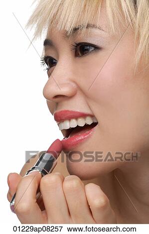 A young woman applies lipstick View Large Photo Image Stock Photo - A young woman applies lipstick. Fotosearch
