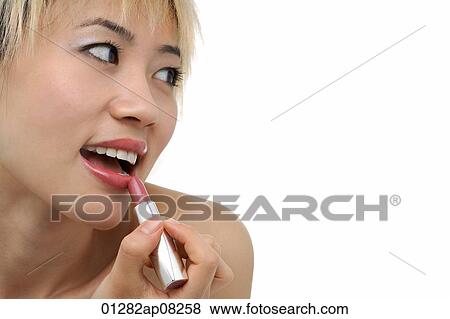 A young woman applies lipstick View Large Photo Image Stock Photo - A young woman applies lipstick. Fotosearch