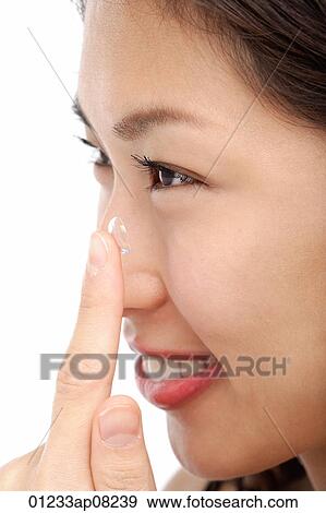 A young woman puts a contact lens in View Large Photo Image Stock Photo - A young woman puts a contact lens in. Fotosearch