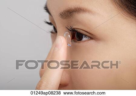 A young woman puts a contact lens in View Large Photo Image Stock Photo - A young woman puts a contact lens in. Fotosearch