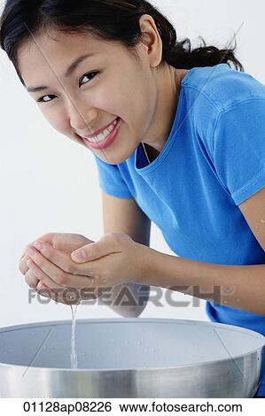 A young woman smiles at the camera as she washes her face View Large Photo Image Stock Photograph - A young woman smiles at the camera as she washes her face. Fotosearch