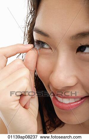 Stock Photo - A young woman takes out her contact lens. Fotosearch