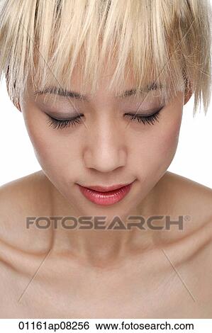 Stock Photograph - A young woman with dyed blonde hair closes her eyes. Fotosearch