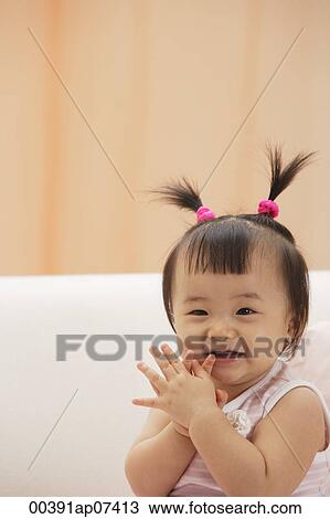Stock Image - Baby Girl clapping hands and laughing, looking at camera. Fotosearch