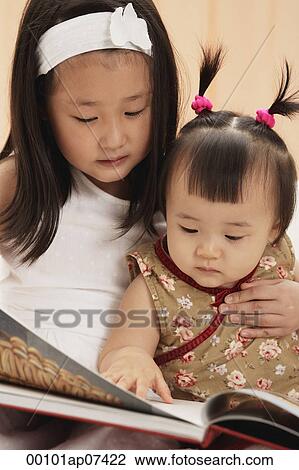 Baby girl with older sister, reading book together View Large Photo Image Stock Image - Baby girl with older sister, reading book together. Fotosearch