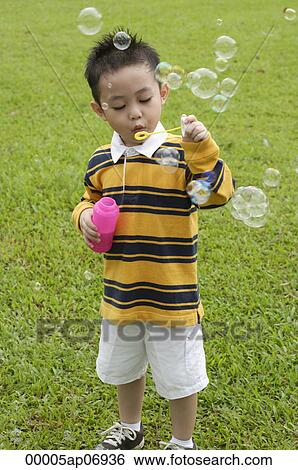 Boy blowing bubbles from bubble wand View Large Photo Image Stock Photograph - Boy blowing bubbles from bubble wand. Fotosearch