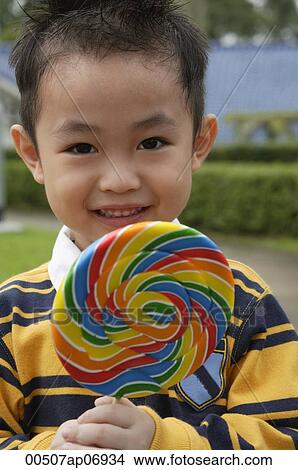 Boy holding colourful lollipop View Large Photo Image Picture - Boy holding colourful lollipop. Fotosearch