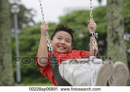 Boy on playground swing, smiling, looking away View Large Photo Image Stock Image - Boy on playground swing, smiling, looking away. Fotosearch