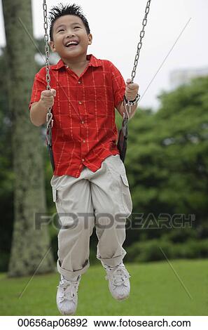 Boy on playground swing, smiling View Large Photo Image Stock Image - Boy on playground swing, smiling. Fotosearch