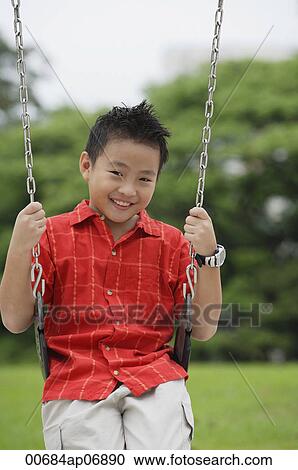 Boy on swing, smiling at camera View Large Photo Image Stock Image - Boy on swing, smiling at camera. Fotosearch