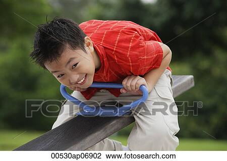 Boy sitting on See-Saw in playground View Large Photo Image Stock Image - Boy sitting on See-Saw in playground. Fotosearch