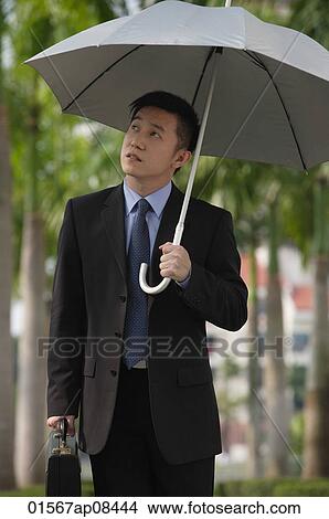 Businessman holding umbrella View Large Photo Image Picture - Businessman holding umbrella. Fotosearch