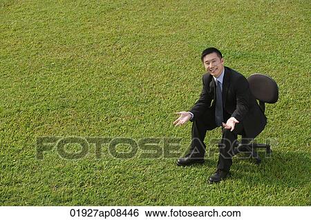 Stock Photograph - Businessman in office chair, smiling at camera. Fotosearch