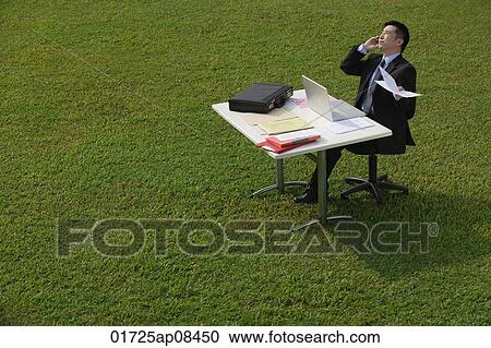 Businessman on the phone while sitting at desk View Large Photo Image Stock Image - Businessman on the phone while sitting at desk. Fotosearch