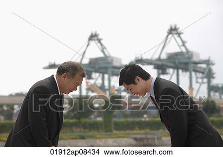 Businessmen standing face to face, bowing View Large Photo Image Picture - Businessmen standing face to face, bowing. Fotosearch