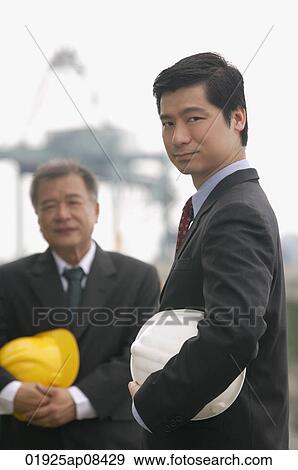 Businessmen with helmets looking at camera View Large Photo Image Stock Photo - Businessmen with helmets looking at camera. Fotosearch