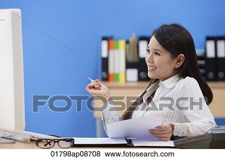 Stock Photo - Businesswoman sitting at desk and looking at computer screen. Fotosearch