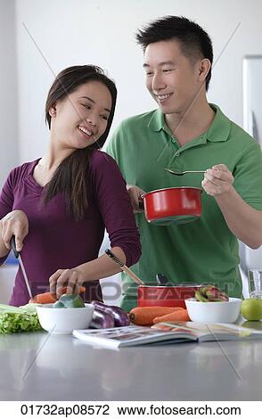 Stock Image - Couple cooking together. Fotosearch