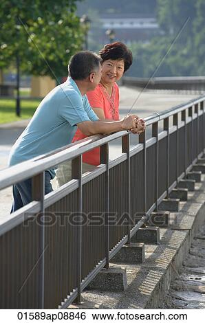 Couple having a conversation while leaning in fence View Large Photo Image Stock Photograph - Couple having a conversation while leaning in fence. Fotosearch