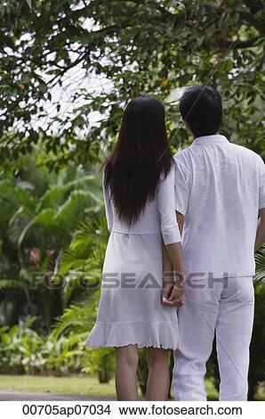 Couple in garden, holding hands, rear view View Large Photo Image Picture - Couple in garden, holding hands, rear view. Fotosearch