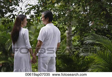 Couple in garden, holding hands, looking at each other View Large Photo Image Stock Photography - Couple in garden, holding hands, looking at each other. Fotosearch