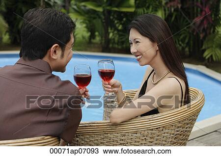 Couple sitting by swimming pool, holding wine glasses View Large Photo Image Stock Image - Couple sitting by swimming pool, holding wine glasses. Fotosearch