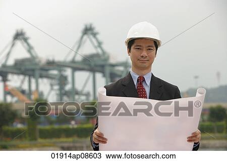 Engineer with plans and hard helmet looking at camera View Large Photo Image Stock Image - Engineer with plans and hard helmet looking at camera. Fotosearch