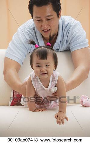 father and baby girl, father holding girl as she crawls on couch View Large Photo Image Stock Photo - father and baby girl, father holding girl as she crawls on couch. Fotosearch