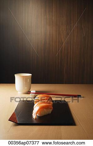 Stock Photo - four pieces of salmon sushi on tray, nigiri on rice ball, chopsticks and tea. Fotosearch