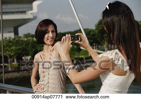 Stock Image - Friends take photos of each other on a bridge. Fotosearch