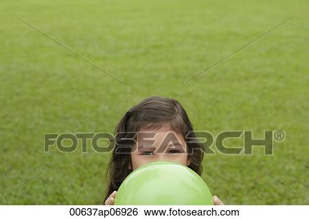 Stock Photograph - Girl hiding behind green balloon. Fotosearch