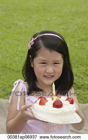 Stock Photo - Girl holding birthday cake with one candle. Fotosearch
