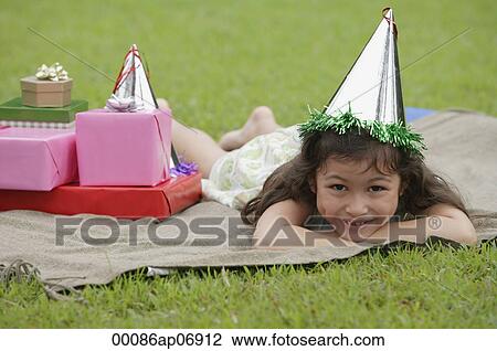 Girl lying on picnic blanket, wearing party hat, smiling at camera View Large Photo Image Stock Image - Girl lying on picnic blanket, wearing party hat, smiling at camera. Fotosearch