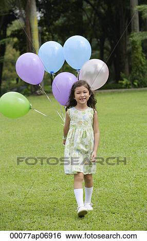 Girl walking on grass, holding a bunch of balloons View Large Photo Image Stock Photograph - Girl walking on grass, holding a bunch of balloons. Fotosearch
