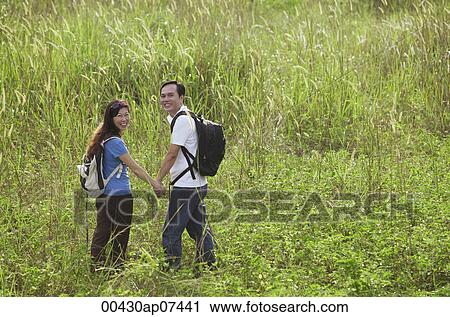 Man and woman hiking through tall grass, nature, outdoors View Large Photo Image Stock Image - Man and woman hiking through tall grass, nature, outdoors. Fotosearch