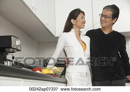 Man and woman in kitchen getting ready for a meal, smiling at each other. View Large Photo Image Stock Photo - Man and woman in kitchen getting ready for a meal, smiling at each other.. Fotosearch