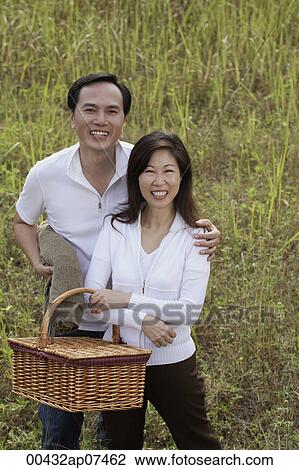 Man and woman standing outdoors in nature, holding picnic basket, smiling at camera View Large Photo Image Stock Image - Man and woman standing outdoors in nature, holding picnic basket, smiling at camera. Fotosearch