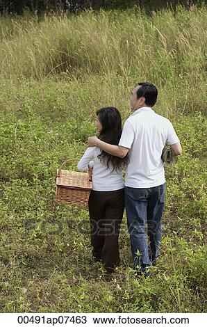 Man and woman walking in nature, holding picnic basket, back to camera View Large Photo Image Stock Image - Man and woman walking in nature, holding picnic basket, back to camera. Fotosearch