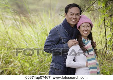 Man and woman wearing hat and scarves, standing outdoors in nature, smiling at camera View Large Photo Image Stock Photo - Man and woman wearing hat and scarves, standing outdoors in nature, smiling at camera. Fotosearch